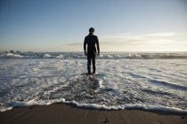 Силуэт человека, стоящего на пляже и смотрящего в океан — стоковое фото