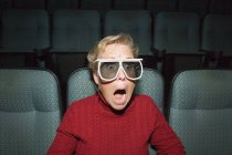Зріла жінка з шокованим виразом у кінотеатрі — стокове фото