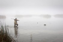 A Hunter In The Water Wearing Camouflage And Holding A Rifle; Colusa, California, United States of America — стоковое фото