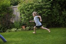 Vista lateral da menina correndo no quintal — Fotografia de Stock