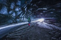 Uomo guarda verso l'ingresso della grotta sotto il ghiaccio del ghiacciaio Canwell nella catena dell'Alaska in inverno. Alaska, Stati Uniti — Foto stock