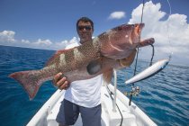 Pescador sosteniendo un pescado fresco capturado Grouper, Tahiti - foto de stock