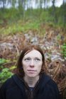 Портрет женщины с рыжими волосами и лесом на заднем плане — стоковое фото