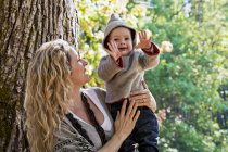 Mother holding son outdoors in a park in autumn — Stock Photo