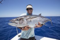 Pescador no barco segurando fresco capturado Dogtooth Tuna — Fotografia de Stock