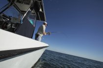 Rear view of fisher on boat at sea — Stock Photo