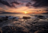 Pôr do sol sobre o oceano com rocha — Fotografia de Stock