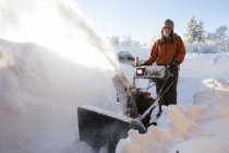 Young woman using a snowblower in the deep snow — Stock Photo