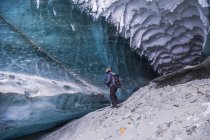 Человек исследует туннель под льдом ледника Кэнвелл на Аляске зимой, Аляска, США — стоковое фото
