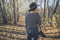 Молода жінка носить капелюх з камерою і прогулянки по лісі біля Печі кондитерські в поле, Фербенкса, Аляска інтер'єру, осінь — стокове фото