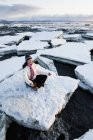Woman practicing meditation on ice chunks stacked against the Homer Spit, Alaska — Stock Photo