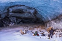Due uomini fanno le valigie dopo aver esplorato una grotta ghiacciata del ghiacciaio Augustana in inverno. Alaska, Stati Uniti d'America — Foto stock