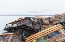 Armadilhas de lagosta empilhadas aleatoriamente ao lado do mar — Fotografia de Stock
