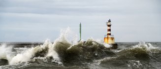 Lighthouse and splashing waves — Stock Photo
