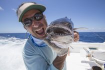 Рыбак на лодке держит свежепойманный Dogtooth Tuna — стоковое фото