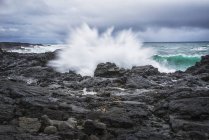 Spruzzi d'onda contro le rocce — Foto stock