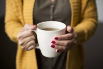 Mujer sosteniendo una taza de té en las manos - foto de stock