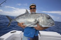 Рыбак держит недавно пойманную гигантскую рыбу Тревалли. Таити — стоковое фото