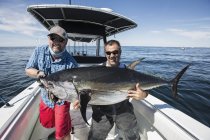 Due pescatori caucasici in possesso di tonno pinna blu sulla barca — Foto stock