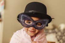 Young girl playing dress up wearing a mask and hat — Stock Photo