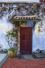 Выцветшая красная дверь окружена голубой стеной в центре Джорджтауна, Пенанг, Малайзия — стоковое фото