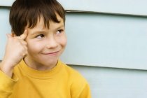 Young Boy Pointing At Head against wall — Stock Photo