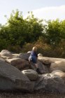Visão traseira do menino caucasiano jovem em pé sobre rochas na natureza — Fotografia de Stock