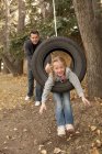 Father pushing daughter on tire swing — Stock Photo