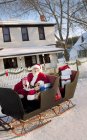 Санта-Клаус на своих санях против дома — стоковое фото