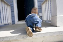 Blick von hinten: Kind krabbelt auf offene Tür zu — Stockfoto