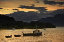 Човни на заході сонця з хмарним небом — стокове фото