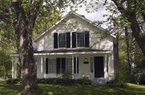 Facade of cottage house in shadows of trees — Stock Photo
