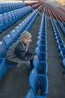 Reife kaukasische Frau sitzt allein im leeren Stadion — Stockfoto