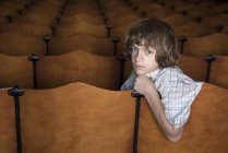 Ребенок, сидящий один на волосах в театре — стоковое фото