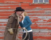 Женщина целует мужчину в ковбойской шляпе за пределами амбара — стоковое фото