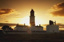 Захід сонця позаду маяк — стокове фото