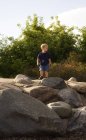 Giovane ragazzo caucasico in piedi su rocce a natura — Foto stock