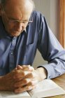Uomo anziano che prega con la Bibbia — Foto stock