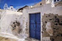 Puertas de madera azul en la pared dañada. Pyrgos, Santorini, Grecia - foto de stock