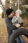 Батько обіймає дочку на гойдалках шин — стокове фото