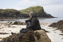 Uomo seduto sulla spiaggia, Isola di Iona, Scozia — Foto stock