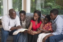 Cristiano afroamericano familia leyendo biblia toogether en casa - foto de stock