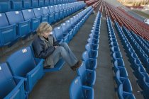 Reife kaukasische Frau sitzt allein im leeren Stadion — Stockfoto