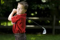 Молодой кавказский мальчик с клюшкой для гольфа на поле — стоковое фото