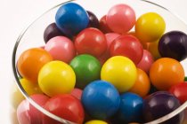 Surtido de bolas de goma de color en vidrio sobre fondo blanco - foto de stock
