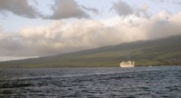 Barco contra costa y colinas - foto de stock