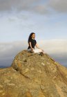 Frau meditiert auf Felsbrocken unter Himmel — Stockfoto