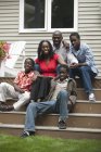 Retrato de la familia afroamericana feliz sentado en las escaleras de su casa y mirando a la cámara - foto de stock