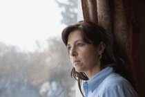 Mitte erwachsene kaukasische Frau lehnt am Fenster — Stockfoto