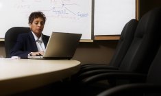 Деловая женщина смешанной расы работает на ноутбуке в зале заседаний — стоковое фото